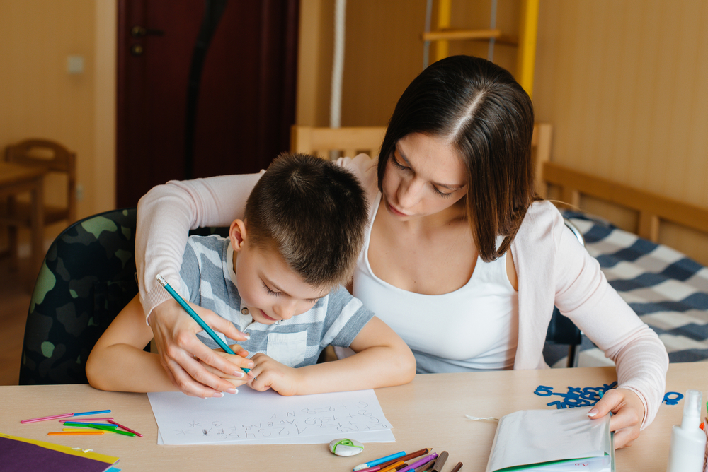 A,Young,Mother,Is,Doing,Homework,With,Her,Son,At